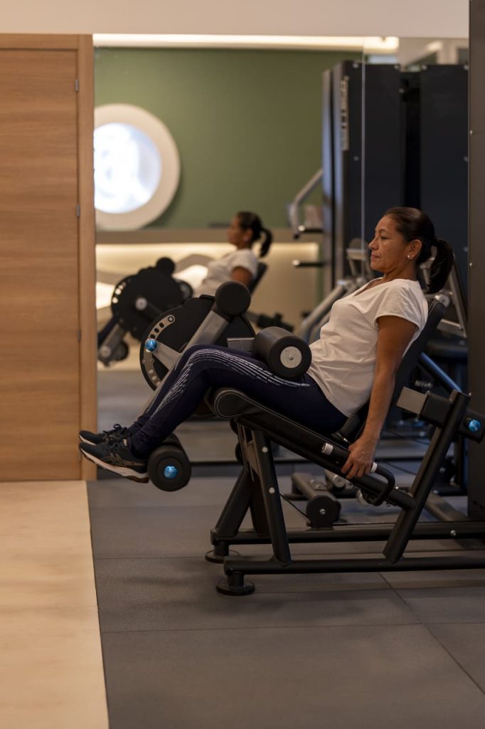 Mujer-realizando-ejercicio-de-piernas-en-maquina-de-clínica-Isabellas